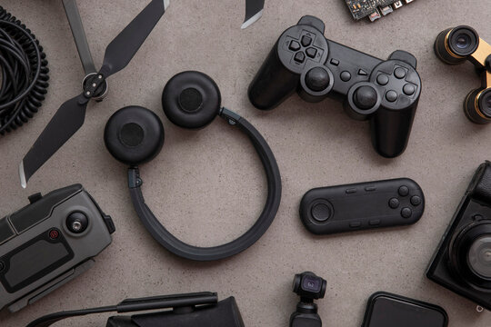 Overhead flat lay of black technology devices and gadgets on a grey background