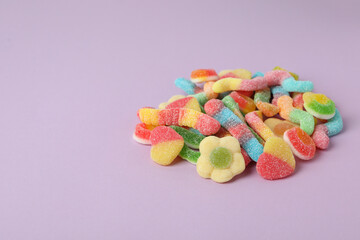 Gummy candies on violet background, space for text