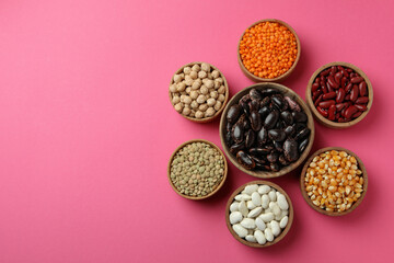 Flat lay composition with different types of beans on pink background