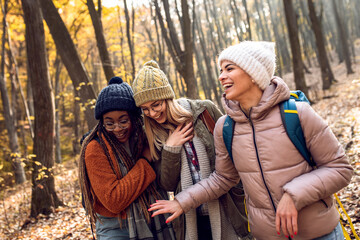 Three female friends having fun and enjoying hiking in forest.