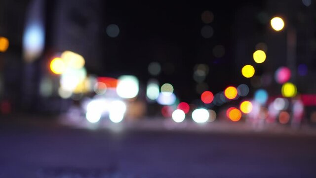 Bokeh on the background of skyscrapers in the city with lights, blurry photo at night. The urban landscape, the movement of cars and people at a busy intersection in the city center.