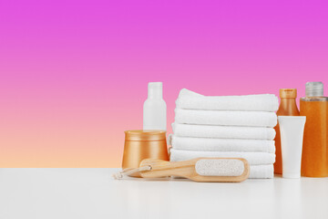 Fototapeta na wymiar Pile of towels, bottles with shampoo on white table