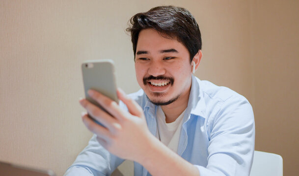 close up young middle eastern man sitting at the coffee cafe and using video call form smartphone to talking with friends and family for new normal and healthy lifestyle concept