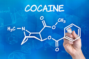 hand with pen drawing the chemical formula of cocaine