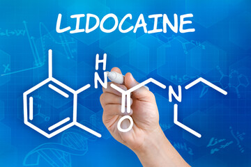 Hand with pen drawing the chemical formula of Lidocaine