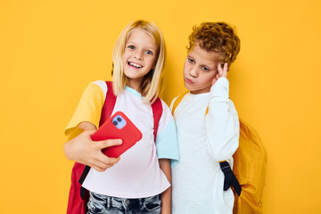 school children looking into a smartphone and playing games yellow background