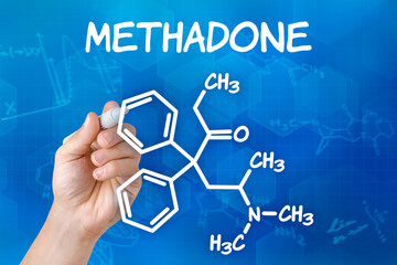 Hand with pen drawing the chemical formula of methadone