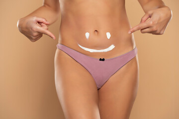 Pretty woman pointing on a smile drawn on her belly