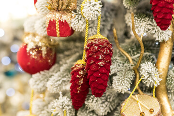 Close up of holidays location with red gold toys, garlands and pine cone on Christmas tree