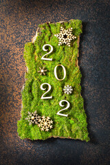 Happy New Year. Festive background with wooden numbers 2022 on artificial moss. Eco-friendly Christmas decorations. Top view.