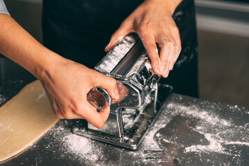 Close up photo of a young woman setting up the pasta making machine.
