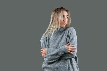 beautiful young woman wearing warm grey sweater posing on grey background, studio shot. concept of...