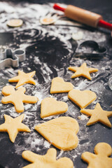 Vertical photo of a table with flour and raw gingerbread biscuits.