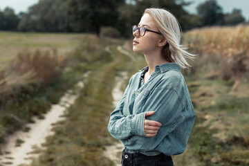 Young stylish woman in blue shirt on countryside road