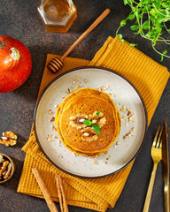 Pumpkin pancakes in a ceramic plate on a dark background top view	