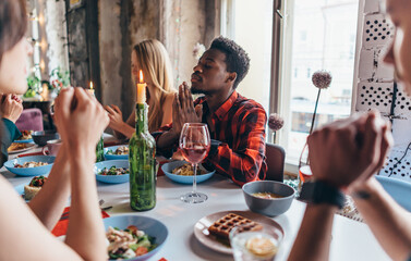 Friends Saying Prayer Before Eating Meal Together.