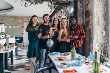 Friends drinking wine toasting while celebrating at restaurant