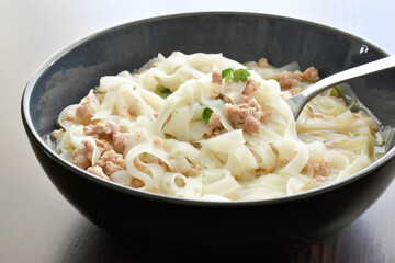 Rice noodles soup with minced pork, coriander and seasoning with a fork.  Asian food style. 