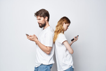 a young couple in white T-shirts with phones in their hands isolated background