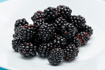 Ripe blackberries on a white plate. Useful forest fruits. Super food. Concept of healthy eating. top view. Close-up. Macro. Blackberry berries with water drops. Flat lay