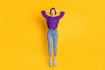 Fototapeta premium Photo portrait full body view of amazed woman holding head with two hands jumping up isolated on vivid yellow colored background