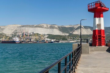 Novorossiysk Commercial Sea Port from side of Western mole. On right is lighthouse. Dry cargo and container ships at berths Port cranes  on shore. Novorossiysk, Russia - September 15, 2021
