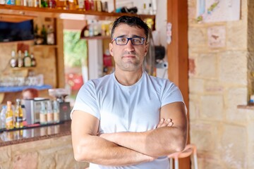 Portrait of positive confident middle aged man wearing glasses with crossed arms