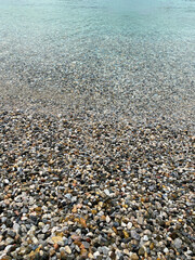 A close up view of smooth polished multicolored stones washed ashore on the beach.