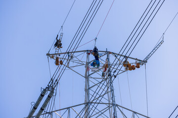 送電鉄塔の最上部で送電線の保守点検をする電力会社の作業員