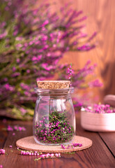 Obraz na płótnie Canvas a glass jar with dried purple heather flowers on a wooden background, herbalism, herbal treatment, aromatherapy