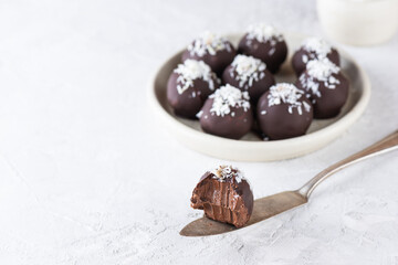 Chocolate truffles with coconut flakes on a light background. Sugar, gluten and lactose free, healthy food.