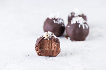 Chocolate truffles with coconut flakes on a light background. Sugar, gluten and lactose free, healthy diet, vegan.