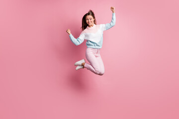 Full length photo of lucky cheerful young woman jump up air raise fists winner isolated on pink...