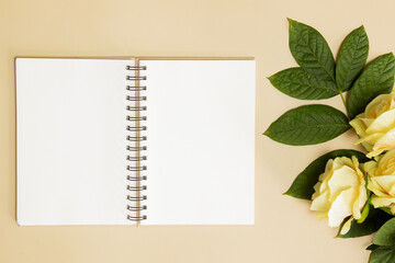 A blank notebook with yellow roses over the brown background. 