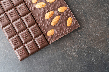 assortment chocolate bars with almonds, handmade sweets. Composition of bars milk and dark almond chocolate on black background, top view. Pastry craft on the table