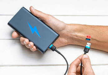 Man is charging from the power bank. The concept of a discharged battery or a decline in strength,...