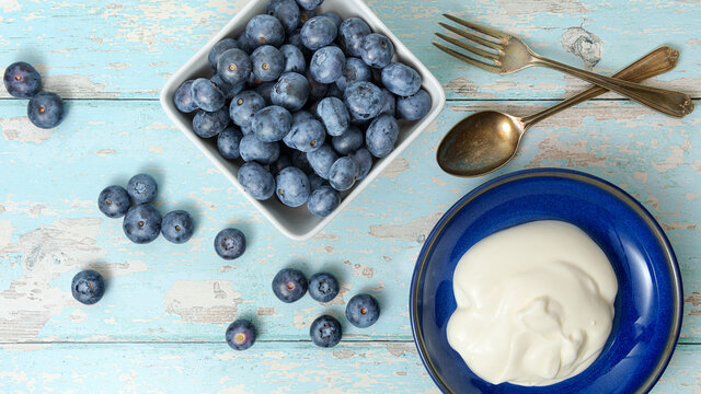A top view, flatlay, overhead view of blueberries on a blue wooden textured background with space for text, 