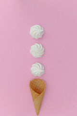An overhead flatlay shot of white meringue nests shot on a pink background