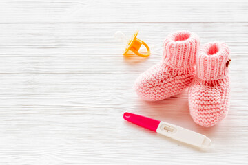 Pink baby girl booties with pregnancy test. Morherhood and pregnancy concept