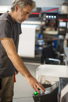 Graphic print technician work on digital t-shirt printing machine printer