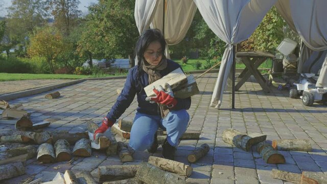 Woman Collects Chopped Firewood Logs