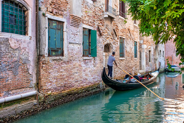 Fototapeta na wymiar Traditional gondolas on the narrow canal in Venice, Italy. Exploring beautiful Venice on water on a sunny day.