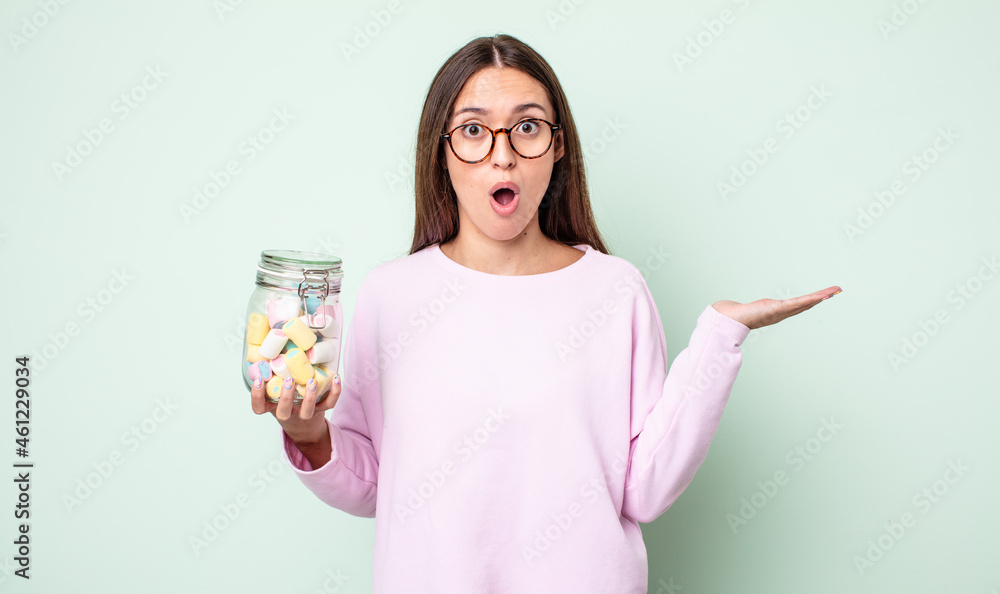 Canvas Prints young pretty woman looking surprised and shocked, with jaw dropped holding an object. jelly candies concept