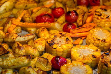 Oven baked vegetables - potatoes, tomatoes, carrots and corn, healthy eating