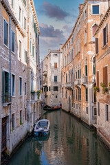 Obraz na płótnie Canvas Traditional gondolas on the narrow canal in Venice, Italy. Exploring beautiful Venice on water on a sunny day.