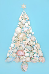 Christmas tree design made from seashells and star decorations on blue background. Abstract alternative concept Xmas tree shape for the holiday season. Flat lay, top view.
