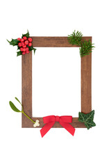 Wooden frame for winter solstice, Christmas and New Year with red bow, holly and European winter greenery. Eco friendly go green concept for the holiday season. On white background, copy space.