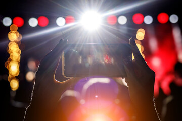 Fan taking photo with smartphone at a concert.