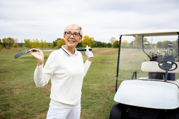 Portrait of an active senior woman playing golf at the golf course and enjoying free time outdoors.
