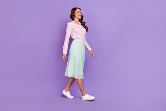 Full length profile photo of nice millennial brunette lady go wear shirt skirt shoes isolated on purple background